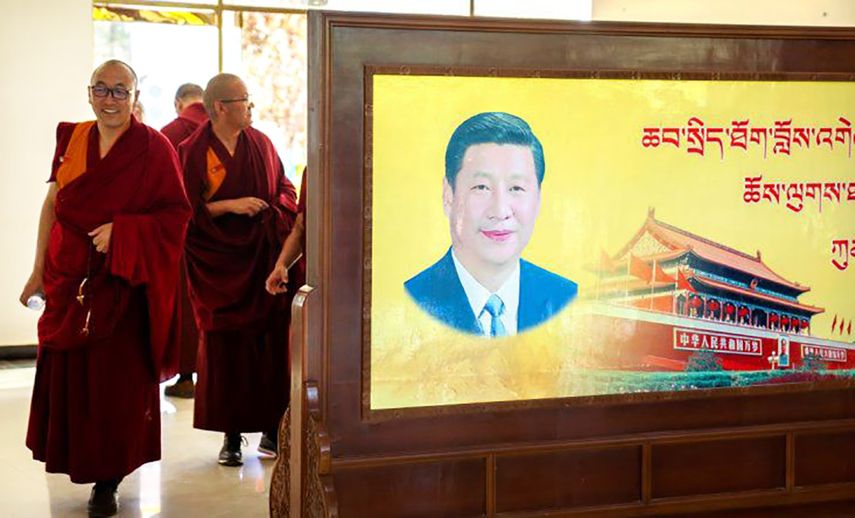 Varios monjes pasan junto a un retrato del presidente chino Xi Jinping