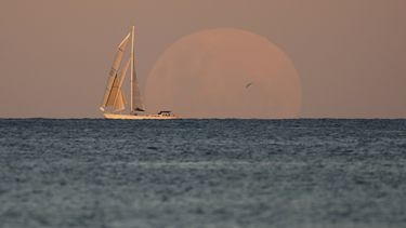Un yate pasa frente a la Luna naciente en Sydney, Australia, miércoles 26 de mayo de 2021. En las próximas horas habrá un eclipse lunar total combinado con una superluna, un acercamiento de la Luna a la Tierra.&nbsp;