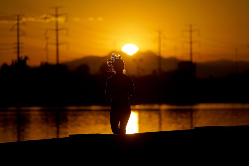 Una mujer corre cerca del Lago Tempe Town al amanecer, el 12 de julio de 2023 en Tempe, Arizona.&nbsp;