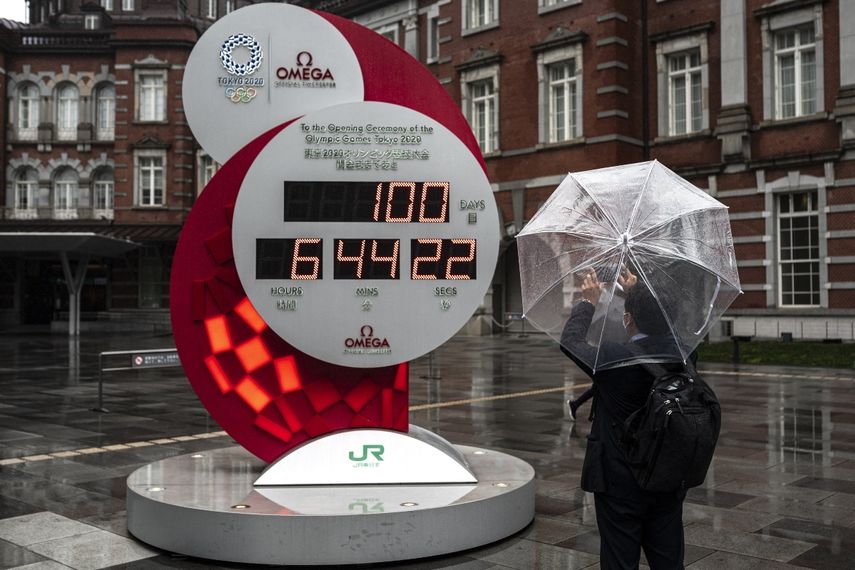 Un hombre toma una foto de un reloj de cuenta regresiva para los Juegos Olímpicos y Paralímpicos de Tokio 2020 100 días antes de la ceremonia de apertura, frente a una estación de Tokio en Tokio el 14 de abril de 2021. &nbsp; &nbsp;