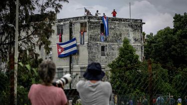 Hombres cuelgan banderas cubanas en las ventanas de la casa del activista opositor Yunior García Aguilera en un intento por evitar que se comunique con el exterior en La Habana, Cuba, el domingo 14 de noviembre de 2021.&nbsp;