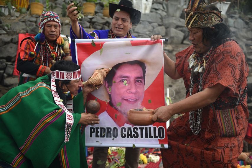 Los chamanes sostienen un cartel del candidato presidencial Pedro Castillo mientras realizan un ritual para predecir el ganador de la próxima segunda vuelta electoral en Perú