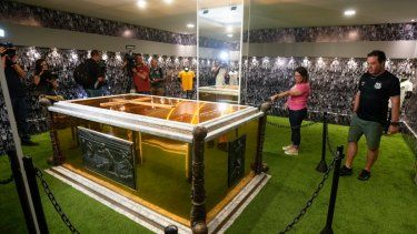 Aficionados parados junto a la tumba del exfutbolista brasileño, Pelé, en el mausoleo construido en el Cementerio Necropole Ecumenica Memorial en Santos, Brasil, el lunes 15 de mayo del 2023.