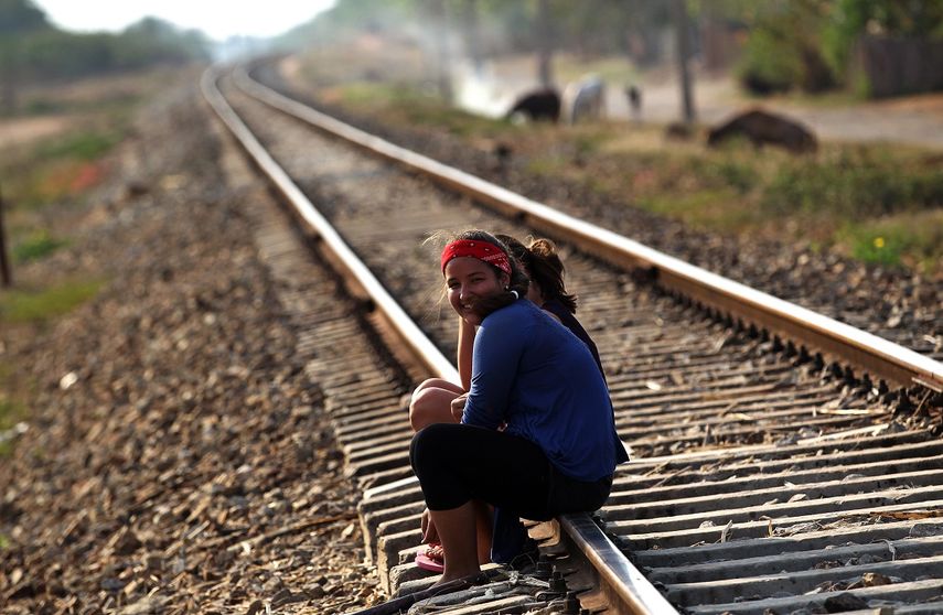 Dos jóvenes cubanas conversan sentadas en las vías del tren en el poblado de Guayacanes, en la central provincia de Ciego de Ávila, un domingo de abril de&nbsp;2017. El servicio ferroviario está entre los que se han visto seriamente afectados por la actual crisis económica de la isla.