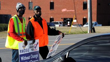 Tray Ragland, izquierda, y Kim Hickerson, del Sindicato para Minoristas, Almacenes y Tiendas Departamentales, portan carteles afuera de las instalaciones de Amazon.