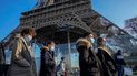 Personas con mascarillas para protegerse del COVID-19 caminan frente a la Torre Eiffel.
