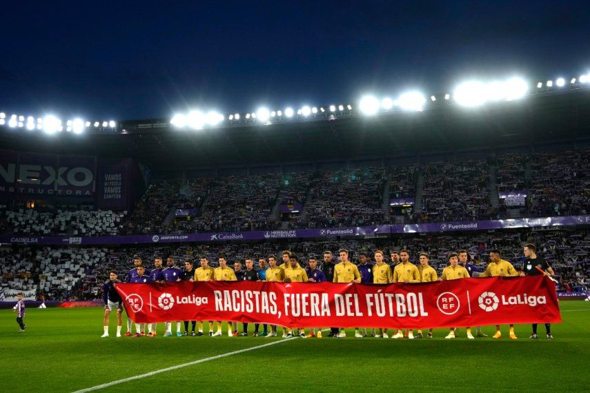 Los jugadores del Barcelona y el Valladolid exhiben una pancarta con la frase Racistas, fuera del fútbol previo al partido de la Liga española, el martes 23 de mayo de 2023, en Valladolid.