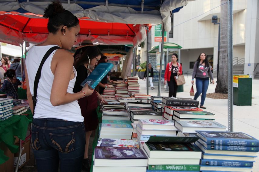 Una mujer lee al dorso de un libro durante la #MiamiBookFair2017.
