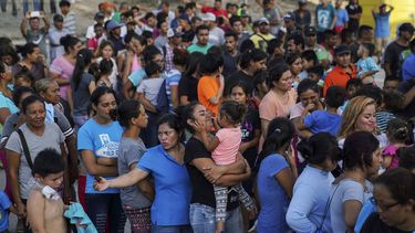 Migrantes, muchos de ellos devueltos a México por la política migratoria del entonces presidente de Estados Unidos Donald Trump, esperan en final para recibir alimentos en un campamento en el puente internacional en Matamoros, México.&nbsp;