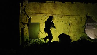 Un miembro de la policía especial de Ucrania camina junto a un edificio destruido mientras patrulla de noche durante un toque de queda en Járkiv, Ucrania, el domingo 27 de marzo de 2022.&nbsp;