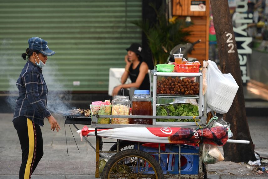 Esta fotografía tomada el 8 de septiembre de 2020 muestra a un vendedor ambulante de comida que vende rollitos de primavera y cerdo a la parrilla en la ciudad de Ho Chi Minh, Vietnam. &nbsp;