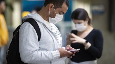 Pasajeros usando mascarillas como precauci&oacute;n contra el contagio del nuevo coronavirus usan sus tel&eacute;fonos en el Aeropuerto Internacional de Sao Paulo, Brasil, el jueves 27 de febrero de 2020.&nbsp;