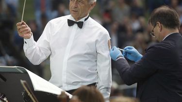 El director Ivan Fischer, fundador de la Orquesta del Festival de Budapest, recibe su tercera dosis de la vacuna contra el COVID-19 mientras dirige a la orquesta en un concierto gratuito al aire libre en Budapest, Hungría, el miércoles 25 de agosto de 2021.