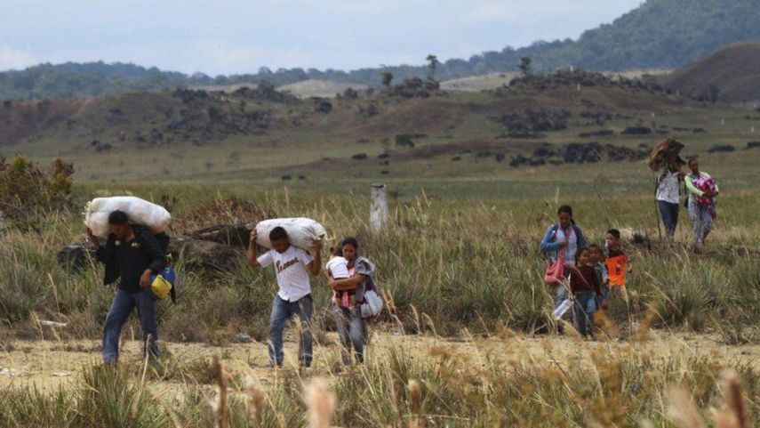 Un grupo de&nbsp;venezolanos camina hacia Brasil a través de un campo, en Pacaraima, estado de Roraima, Brasil, el viernes 22 de febrero de 2019.