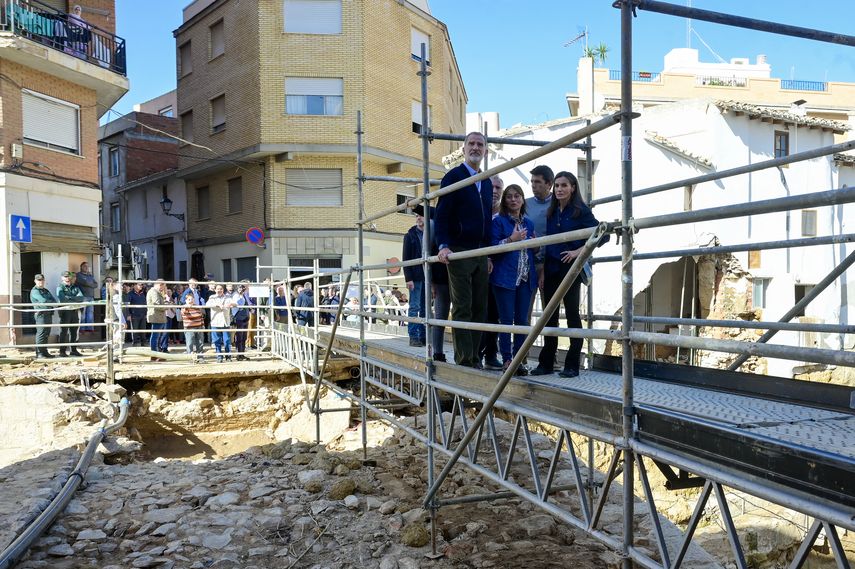 El rey de España Felipe VI y la reina Letizia cruzan un puente improvisado durante una visita a la ciudad de Chiva, dañada por las inundaciones, en la región de Valencia, este de España, tras las catastróficas inundaciones mortales, el 19 de noviembre de 2024.