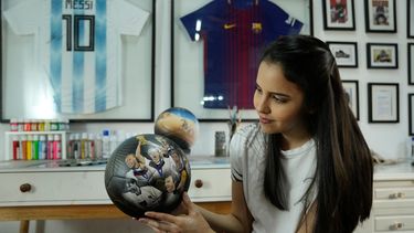 La artista plástica paraguaya Lili Cantero sostiene un balón de fútbol pintado a mano e ilustrado con integrantes de la selección de Alemania que disputó la Copa del Mundo de 2014, en San Lorenzo, Paraguay, el jueves 10 de noviembre de 2022.