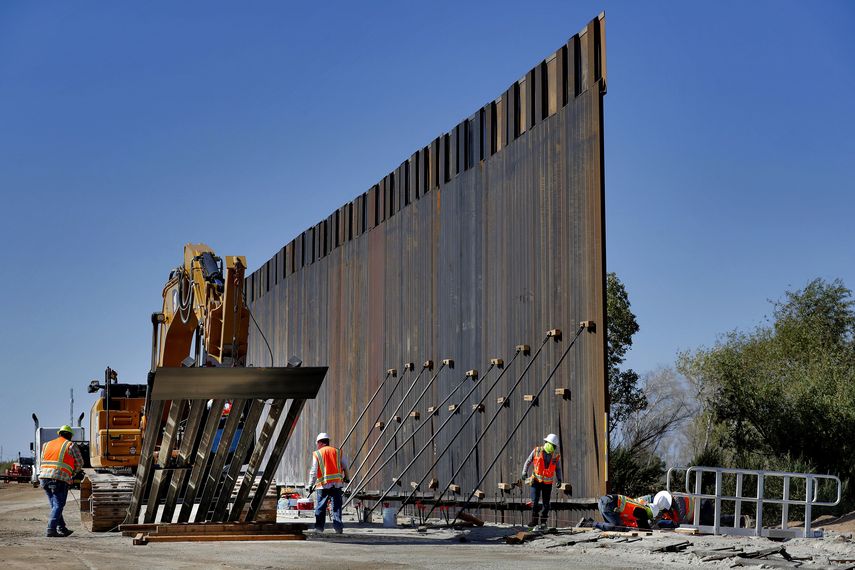 Con la ayuda a una gr&uacute;a gigantesca, trabajadores instalan secciones de un muro pensado para frenar el cruce ilegal de inmigrantes en la frontera&nbsp;