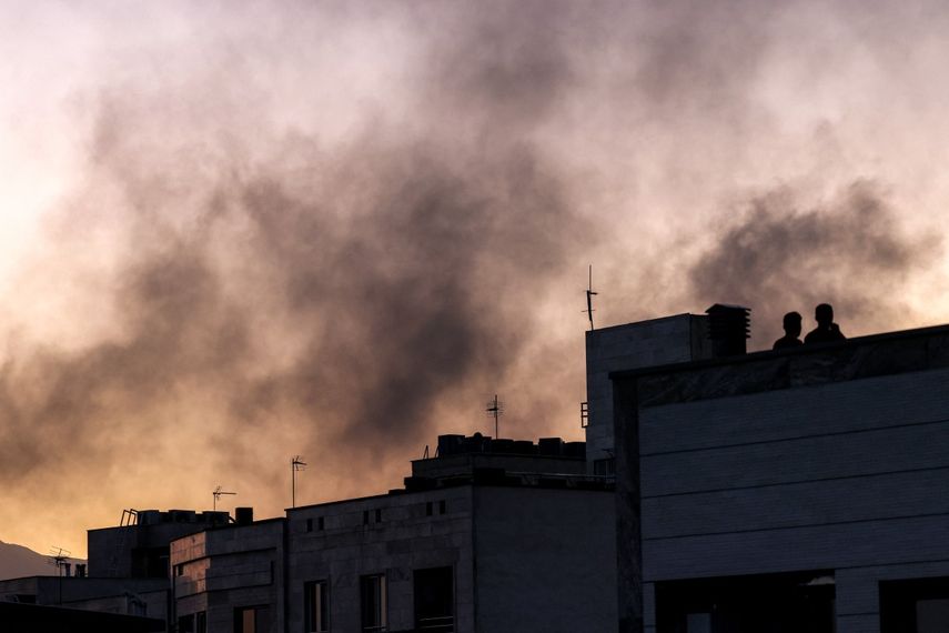 Personas en un tejado en medio de una columna de humo tras un ataque israelí en Teherán, Irán, el 17 de junio de 2025.