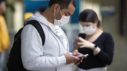 Pasajeros usando mascarillas como precauci&oacute;n contra el contagio del nuevo coronavirus usan sus tel&eacute;fonos en el Aeropuerto Internacional de Sao Paulo, Brasil, el jueves 27 de febrero de 2020.&nbsp;