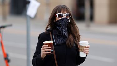 &nbsp; Una mujer con tapabocas lleva dos caf&eacute;s que acaba de comprar en una cafeter&iacute;a de Denver, que lentamiente empieza a reabrir sus negocios, el 13 de mayo del 2020. A medida que se vuelve a la normalidad tras las cuarentenas por el coronavirus, la gente tiene que decidir si vale la pena exponerse a contraer el virus, que sigue dando vueltas, o es preferible permanecer m&aacute;s tiepo en casa.&nbsp;