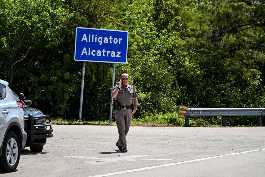 Un oficial de la Patrulla de Carreteras de Florida observa mientras un grupo de manifestantes se reúnen para exigir el cierre del centro de detención de inmigrantes conocido como Alligator Alcatraz en el condado Dade-Collier en Florida.