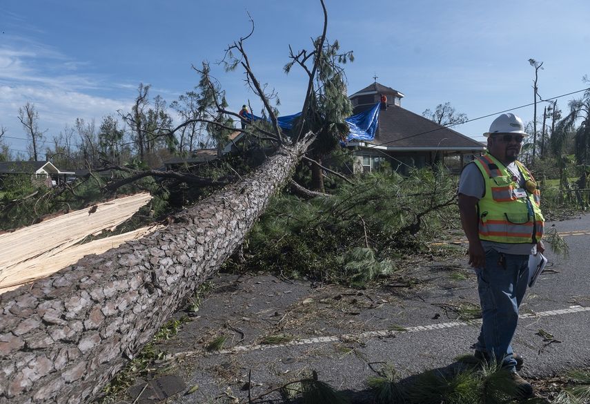Un empleado de una compa&ntilde;&iacute;a de electricidad examina los da&ntilde;os causados a las l&iacute;neas el&eacute;ctricas junto a un &aacute;rbol grande que cay&oacute; sobre una casa despu&eacute;s del paso del hurac&aacute;n Laura en Lake Charles el 27 de agosto de 2020.&nbsp;