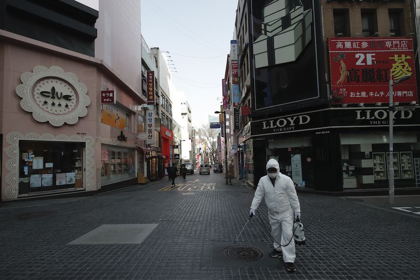 Un operario, vestido con un traje de protecci&oacute;n, desinfecta una calle como medida de precauci&oacute;n contra la propagaci&oacute;n de un nuevo coronavirus, en un distrito comercial en Se&uacute;l, Corea de Sur, el 20 de marzo de 2020.&nbsp;