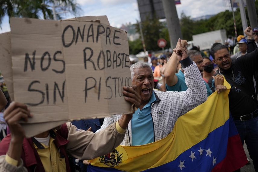 Los trabajadores públicos jubilados gritan la consigna española ¡El pueblo unido jamás será vencido! durante una protesta de trabajadores públicos exigiendo que el gobierno pague todos sus beneficios y respete los convenios colectivos en Caracas, Venezuela, el jueves 11 de agosto de 2022. El letrero dice en español ONAPRE, nos robaste sin un arma, refiriéndose a la oficina nacional de presupuesto.&nbsp;