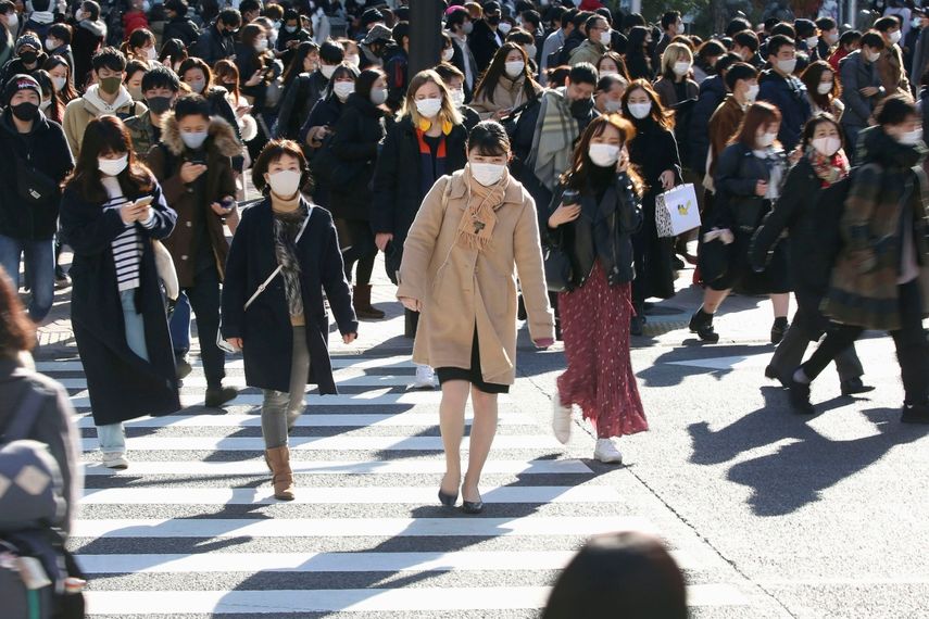 Decenas de personas con mascarillas para frenar la propagación del coronavirus cruzan una intersección concurrida del distrito comercial de Shibuya, en Tokio, el sábado 26 de diciembre de 2020