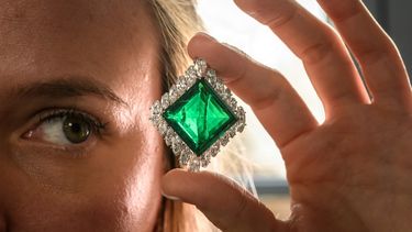Una empleada de Christies posa con The Aga Khan Emerald, un broche de Cartier con esmeraldas y diamantes elaborado con una esmeralda cuadrada de 37,00 quilates, diamantes en forma de marquesa, platino y oro amarillo de 18 quilates durante una presentación de prensa en Ginebra, el 7 de noviembre de 2024. &nbsp;