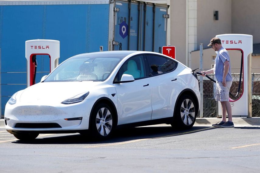 El conductor de un auto de Tesla recarga las baterías de su auto.