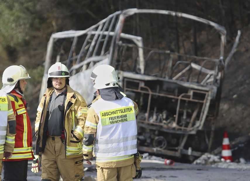 Los bomberos atienden la emergencia, mientras al fondo se ve el bus totalmente quemado.&nbsp;