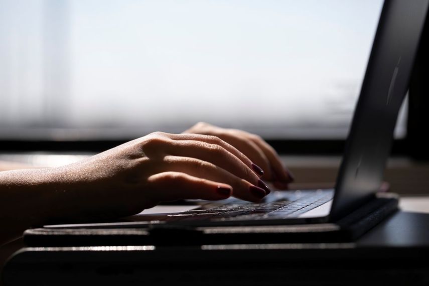 Una mujer escribe es su laptop, conectada a internet.
