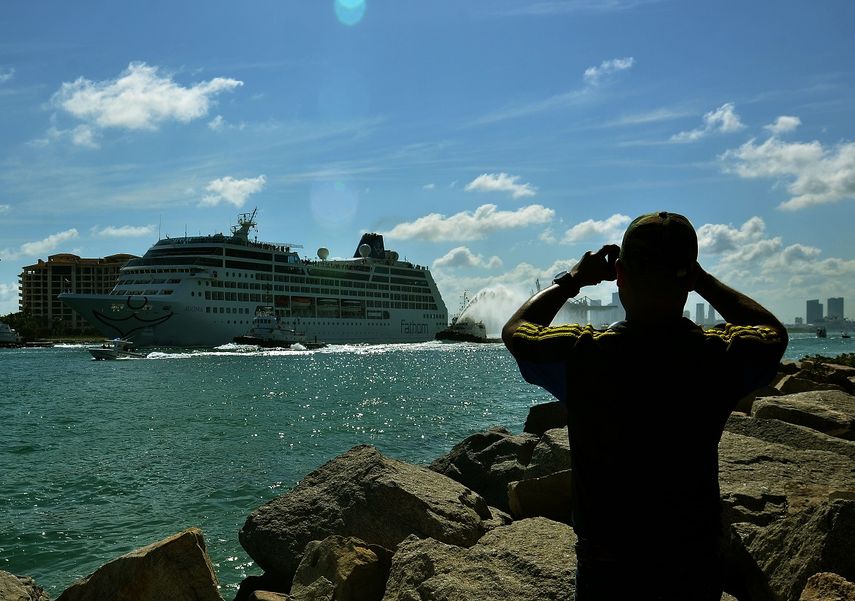 Un hombre toma una fotografía al crucero Adonia, de la compañía Fathom, filial de Carnival, a su salida del puerto de Miami.