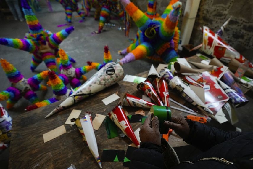 Un artesano de piñatas trabaja una con la forma tradicional, una esfera con siete picos, en un pequeño negocio familiar en Acolman, al norte de Ciudad de México, el miércoles 13 de diciembre de 2023. Esta artesanía tradicional tiene un origen religioso y está cargada de simbolismo: cada cono representa uno de los siete pecados capitales, por eso se golpea la piñata hasta destruirla como una forma de alejarse de esos pecados.