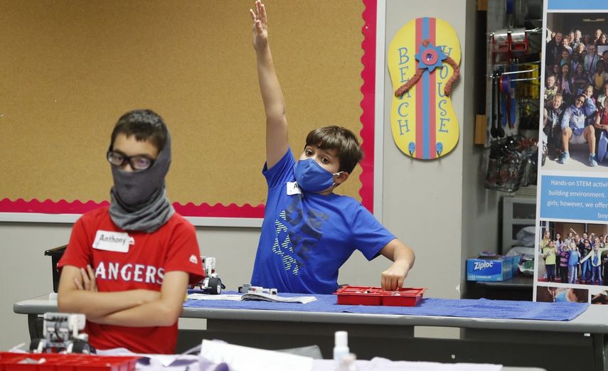 En esta imagen del martes 14 de julio de 2020, Aiden Trabucco utiliza una mascarilla para protegerse del coronavirus mientras levanta la mano para hacer una pregunta detr&aacute;s de Anthony Gonzales, durante un campamento de verano en la escuela secundaria Wylie, en Wylie, Texas.&nbsp;