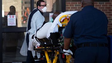 El param&eacute;dico del departamento de Bomberos del condado de Arlington, Ben Bieber (derecha) y Brian Holmes, trasladan a un paciente con problemas respiratorios desde la ambulancia a un hospital de Arlington, Virginia, el 9 de abril de 2020.