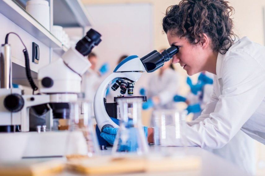 Una científica observa a través de un microscópio.&nbsp;