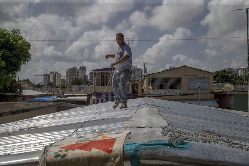 Jorge Ortiz trabaja para proteger el techo de su vivienda ante la inminente llegada de la tormenta tropical Dorian en el vecindario Martín Peña, en San Juan, Puerto Rico, el martes 27 de agosto de 2019.&nbsp;