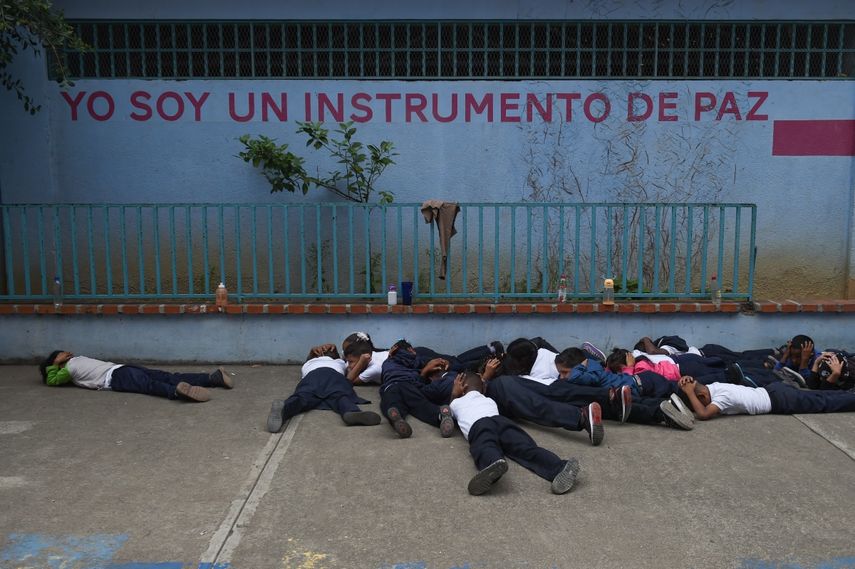 Un grupo de niños de primaria yace en el piso del patio de recreo durante un simulacro de tiroteo en la escuela Manuel Aguirre en el barrio La Bombilla en Caracas el 23 de febrero de 2023. Los simulacros de tiroteos organizados por el Comité Internacional de la Cruz Roja (CICR) se están llevando a cabo en escuelas de algunos de los barrios más violentos de Caracas. Simulacros de seguridad similares ocurren en otros países latinoamericanos con altos niveles de violencia, como Brasil y México.