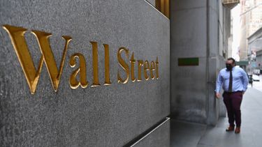 Un hombre camina cerca de la entrada principal de Wall Street.