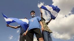Tres jóvenes ondean banderas nacionales durante una protesta para exigir que el régimen libere a cientos de manifestantes detenidos, en Managua, Nicaragua, el sábado 16 de marzo de 2019.