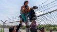 Migrantes cruzan una valla de alambre de púas después de pasar el Río Grande hacia Estados Unidos desde México, en Eagle Pass, Texas, el 25 de agosto de 2023.