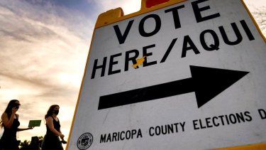 Dos votantes entregan su papeleta en una casilla electoral, el 3 de noviembre de 2020, en Tempe, Arizona.