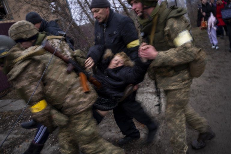 Soldados ucranianos cargan a una mujer enferma semiconsciente mientras cruzan el río Irpin mientras huyen de la ciudad en las afueras de Kiev, Ucrania, el sábado 5 de marzo de 2022. 