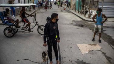 Con una máscara facial en medio de la pandemia del nuevo coronavirus, el buzo Yuniel González camina a casa con su pesca del día en La Habana, Cuba, el martes 27 de octubre de 2020.