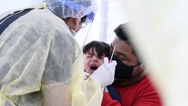 En esta foto de archivo tomada el 28 de abril de 2020, Jos&eacute; Vatres (R) sostiene a su hijo Aidin, quien reacciona como la enfermera practicante Alexander Panis (L) toma una muestra de hisopo nasal para detectar COVID-19 en una estaci&oacute;n m&oacute;vil de pruebas en un estacionamiento de una escuela p&uacute;blica &aacute;rea en Compton, California, justo al sur de Los &Aacute;ngeles. Los ni&ntilde;os menores de cinco a&ntilde;os tienen entre 10 y 100 veces mayores niveles de material gen&eacute;tico del coronavirus en la nariz en comparaci&oacute;n con los ni&ntilde;os mayores y los adultos, seg&uacute;n un estudio realizado en JAMA Pediatrics el 30 de julio de 2020.&nbsp;