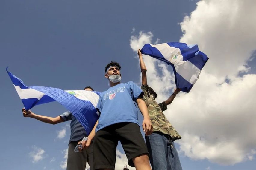 Tres jóvenes ondean banderas nacionales durante una protesta para exigir que el régimen libere a cientos de manifestantes detenidos, en Managua, Nicaragua, el sábado 16 de marzo de 2019.