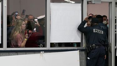 Múltiples personas observan a través de las ventanas de una oficina electoral el miércoles 4 de noviembre de 2020 mientras la policía impide que pasen, en Detroit.&nbsp;