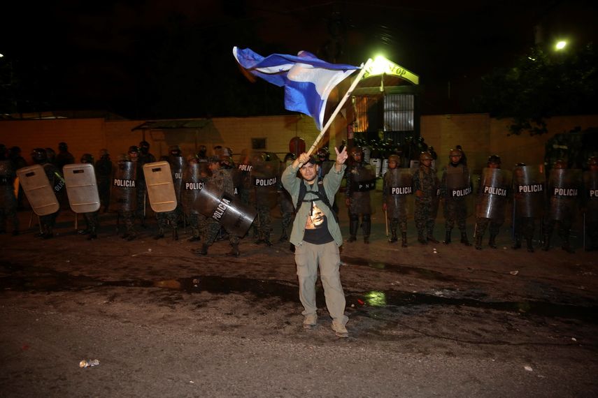 Un simpatizante del candidato opositor Salvador Nasralla, iza una bandera hondureña frente al cordón policial durante los enfrentamientos que se produjeron entre grupos de seguidores del candidato opositor Salvador Nasralla y las fuerzas de seguridad.&nbsp;